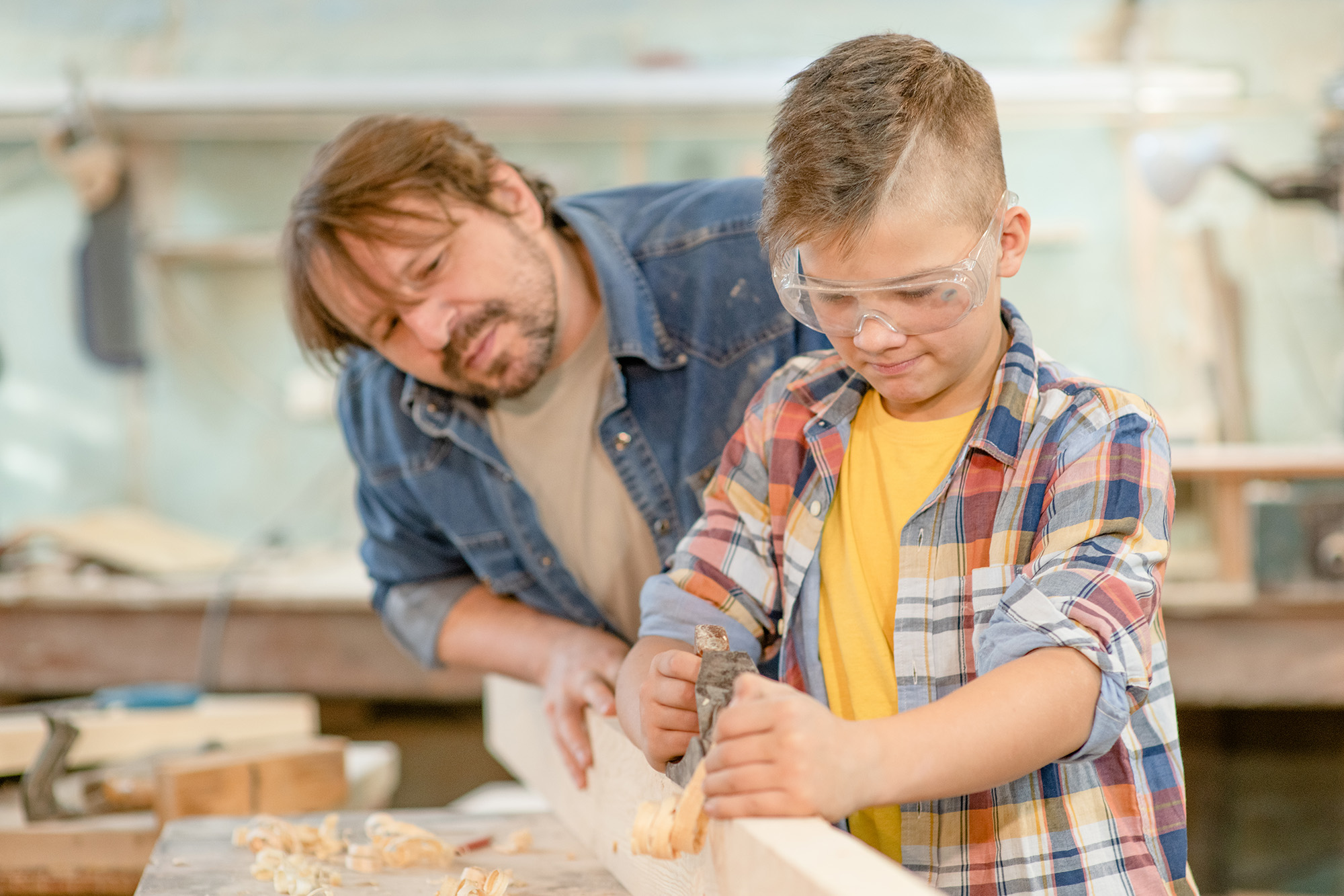 A man teaching a teenage boy carpentry