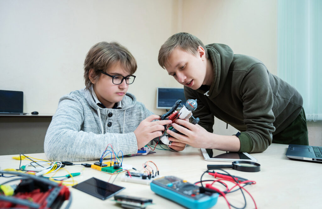 Teenager boy with instructor at robotics school