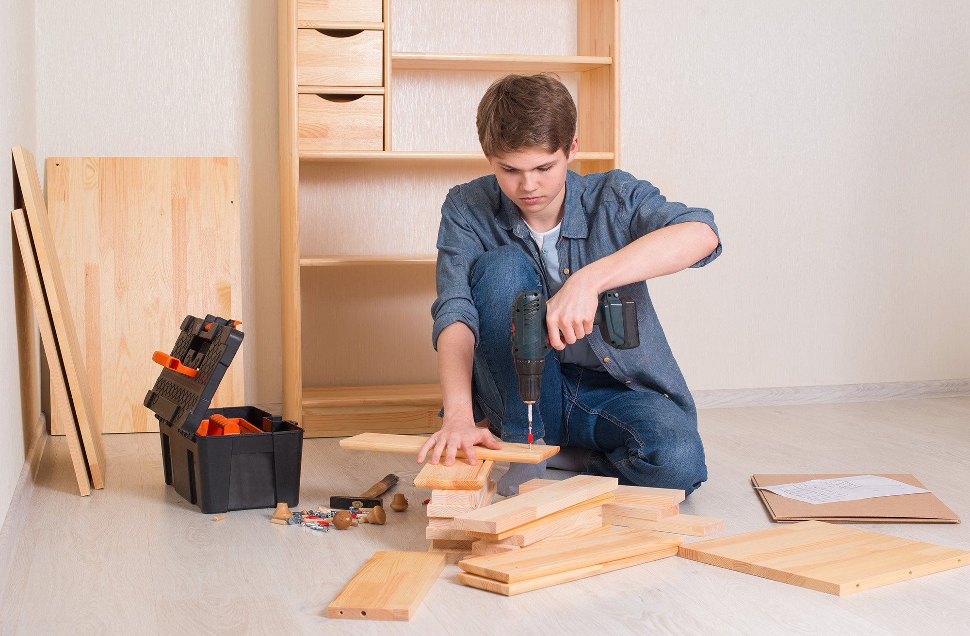 Young teenager boy assembling furniture at home