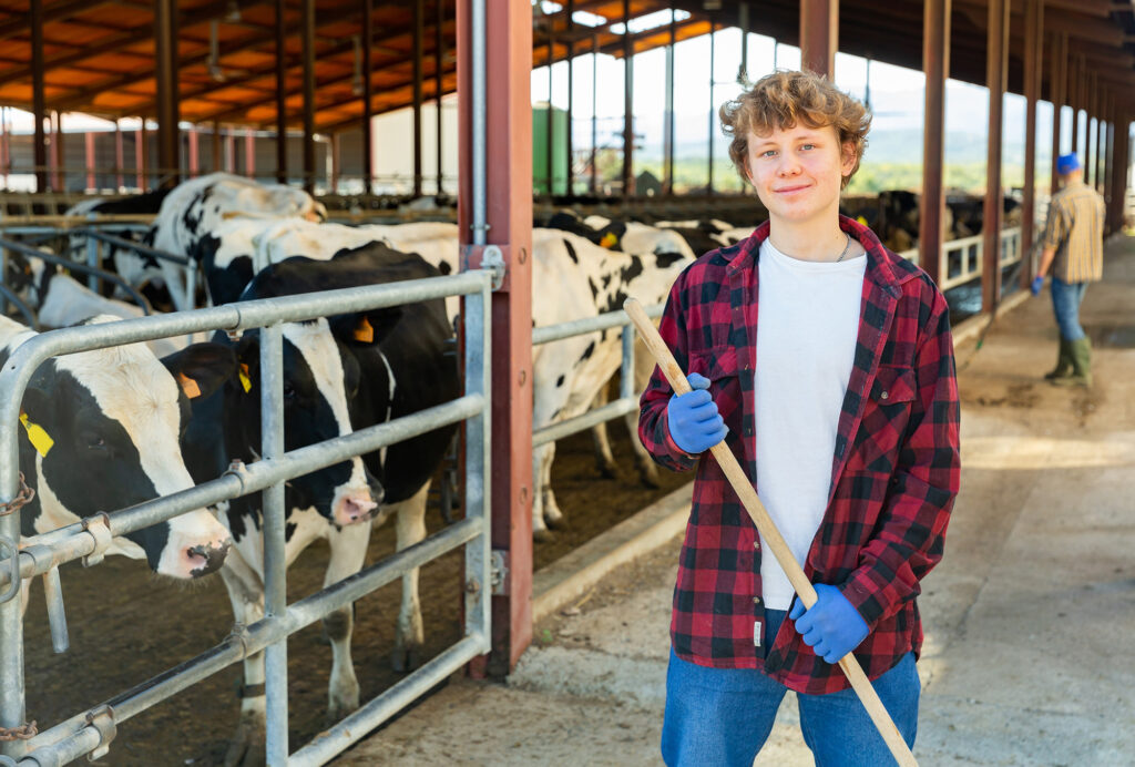 Portrait of confident smiling teen boy working in outdoor cowshed